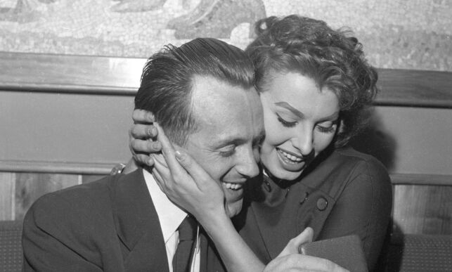 CORTINA, ITALIA OL i Cortina Februar 1956.
Langrennsløper Hallgeir Brenden holder rundt skuespillerinnen Sophia Loren. Brenden feirer gullet på 15 kilometer langrenn. HEr studerer de Brendens OL-medalje.
Foto: NTB / Scanpix